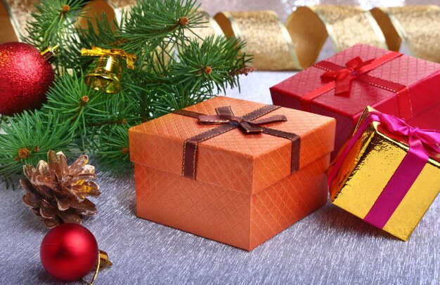 Świąteczna dekoracja z pudełkami prezentowymi, kolorowymi bombkami, choinką i szyszkami na rozmytym, błyszczącym i bajecznym