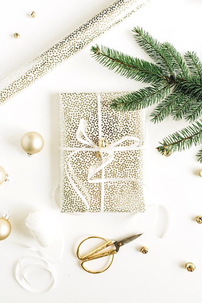 Świąteczna kompozycja świąteczna z pudełkiem, gałązkami jodły i złotymi dekoracjami na białej powierzchni. Widok z góry na płasko