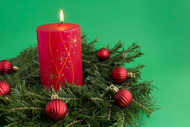 Świąteczna kompozycja z pierścionkiem bożonarodzeniowym lub wieńcem i czerwoną płonącą świecą na zielonym tle Kopiowanie miejsca Zbliżenie