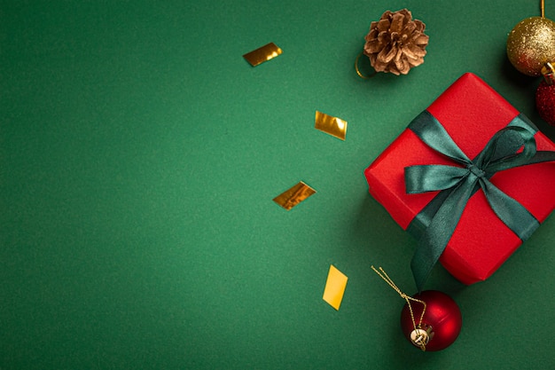 Świąteczna kompozycja z prezentem i dekoracjami w czerwono-zielonej złotej kolorystyce