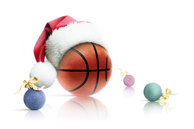 Świąteczna koszykówka. Piłka do koszykówki w Santa hat Boże Narodzenie zabawki na białym tle. Odosobniony
