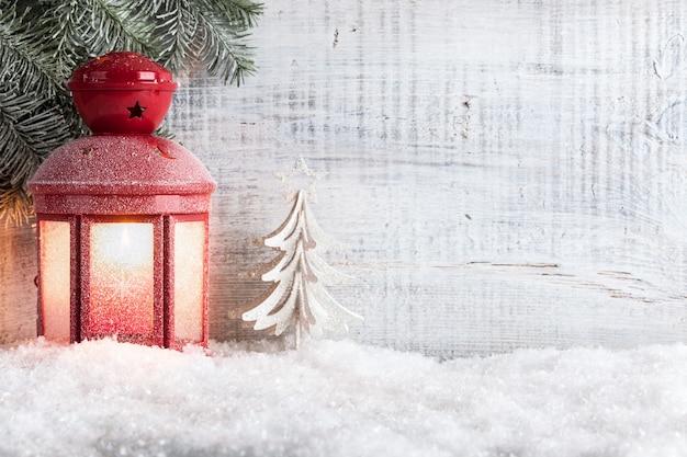 Świąteczna latarnia świeca na śniegu i drewnianym tle