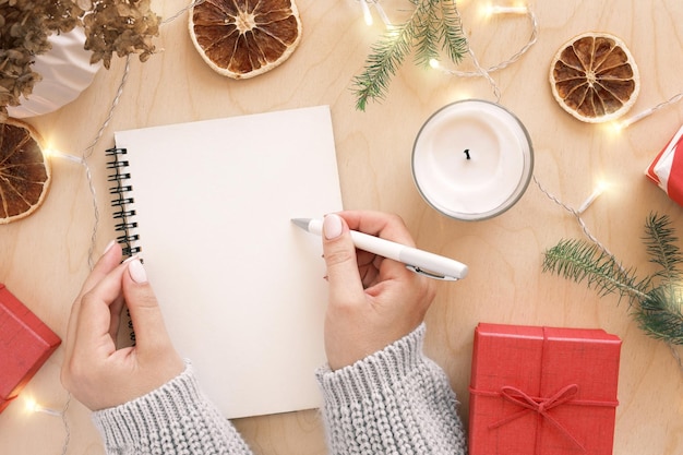 Świąteczna lista życzeń pisania Kobieta tworząca listę prezentów na ferie zimowe Widok z góry płasko leżący Przygotowanie do koncepcji Boże Narodzenie i nowy rok
