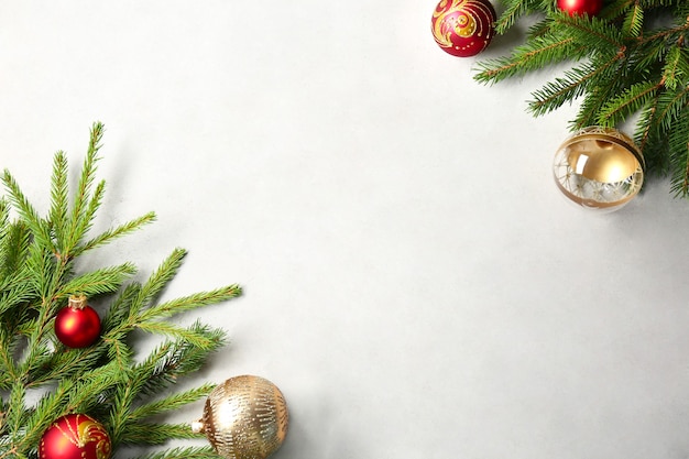 Świąteczna ramka z gałęzi jodłowych i bombki dekoracyjne na jasnym tle