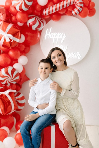 Świąteczna sesja zdjęciowa mamy i syna. Strefa zdjęć balonów z czerwonymi i białymi dekoracjami świątecznymi