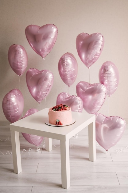 Świąteczna strefa zdjęć z sercami z balonów z helem na urodziny obok tortu
