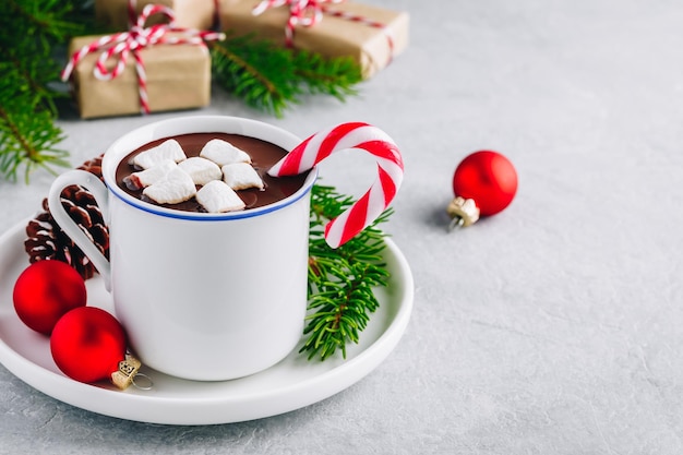 Świąteczna świąteczna gorąca czekolada z pianką marshmallow i cukrową laską na szarym betonowym kamiennym tle