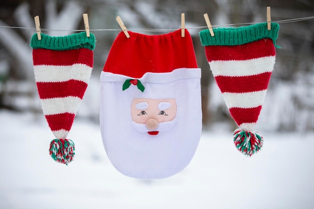 Świąteczna torba Świętego Mikołaja i czapki w paski są suszone na linie Przygotowanie do świętowania Bożego Narodzenia