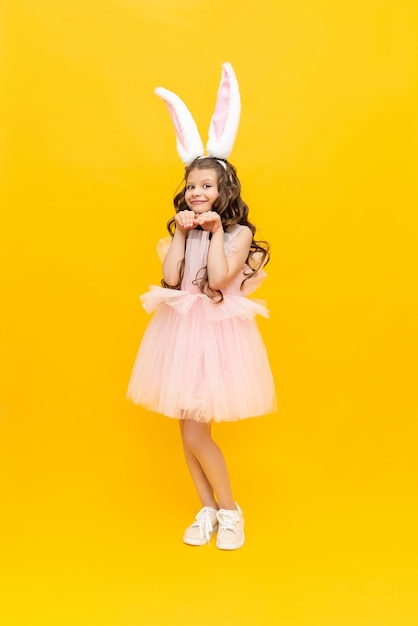 Świąteczna Wielkanoc Nastolatka w puszystej sukience z uszami królika uśmiecha się szeroko Piękna mała dziewczynka w kostiumie królika na żółtym odosobnionym tle pełnej długości