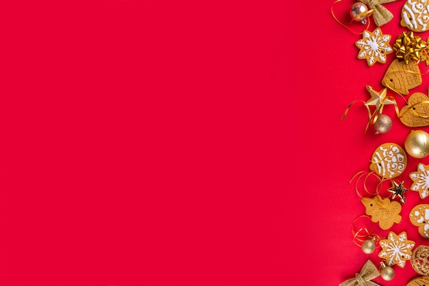 Zdjęcie Świąteczne ciasteczka noworoczne ciasteczka gingerbread z świątecznymi złotymi dekoracjami i baubles na czerwonym tle karta świąteczna z ciasteczkami gingerbread widok górny przestrzeń kopiowania