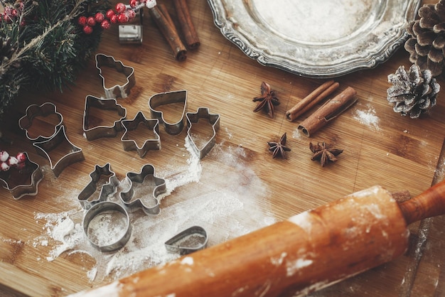 Świąteczne ciasteczka z piernika na rustykalnym stole z drewnianym wałkiem cynamonowe szyszki anyżowe ozdoby choinkowe vintage talerz Atmosferyczny stylowy obraz ferie zimowe