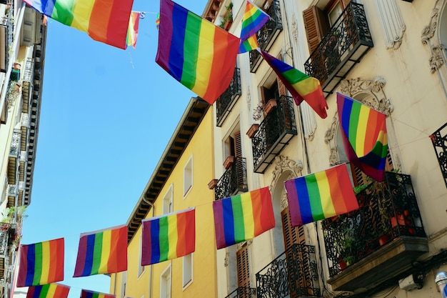 Świąteczne flagi społeczności LGBTQ wiszą między eleganckimi budynkami retro w gejowskiej dzielnicy Madrytu w Hiszpanii