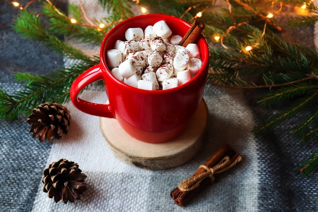 Świąteczne gorące napoje. Gorące kakao w czerwonym kubku z piankami i cynamonem na świątecznie