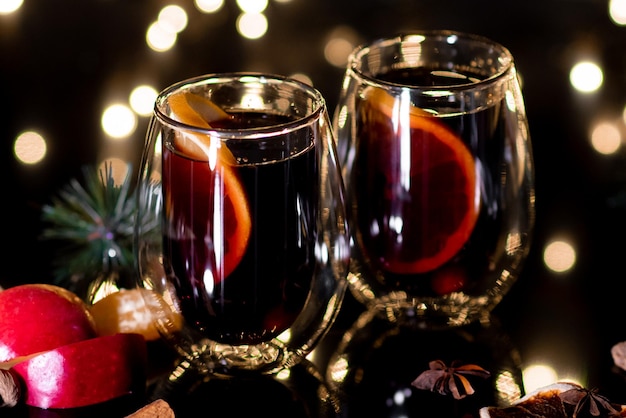 Świąteczne grzane wino z czerwonego wina z przyprawami i owocami na czarnym tle