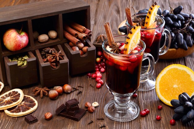 Świąteczne Grzane Wino Z Jabłkiem, żurawiną, Pomarańczą, Przyprawami I Czekoladą Na Drewnianym Stole