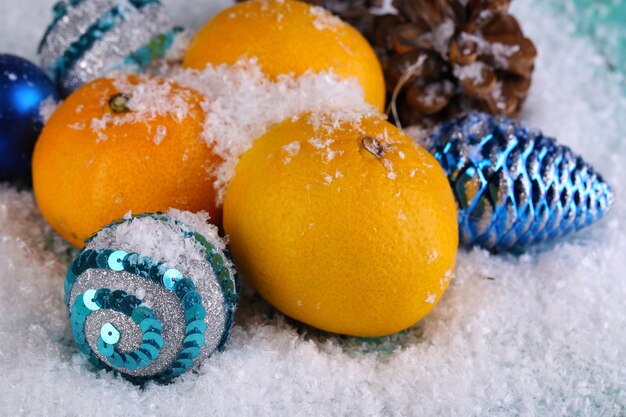 Świąteczne mandarynki i świąteczne zabawki na drewnianym stole na śniegu