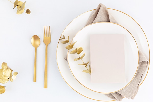 Świąteczne nakrycie stołu ze złotymi sztućcami i porcelanowym talerzem