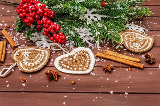 Świąteczne ozdoby. Choinka noworoczna, świeże liście, szydełkowane serca imbirowe ciasteczka, przyprawy i sztuczny śnieg.