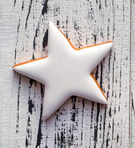 Świąteczne pierniczki w kształcie gwiazdy na białym drewnianym tle.