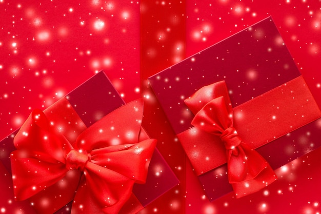 Świąteczne prezenty i świecący śnieg na czerwonym tle Prezenty świąteczne niespodzianka