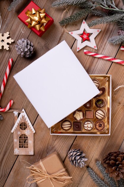 Świąteczne pudełko czekoladowych cukierków na drewnianym stole z sezonową dekoracją świąteczną
