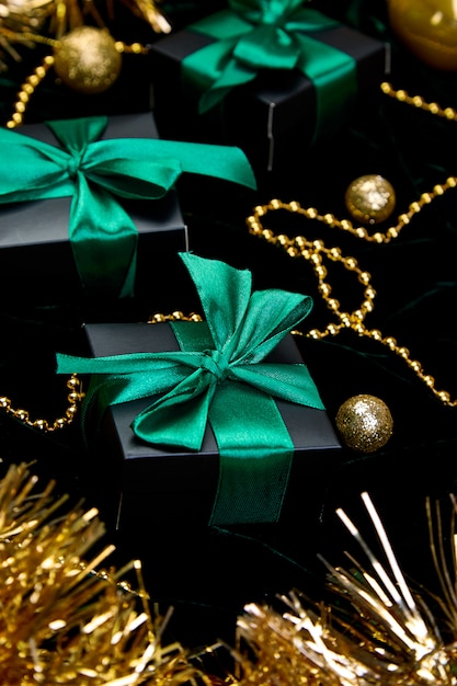 Świąteczne świąteczne czarne pudełka z zieloną wstążką na welurowym blasku