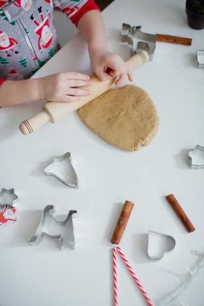 Świąteczne tło do pieczenia ciasta foremki do ciastek przyprawy i ozdoby świąteczne Childs robi ciasteczka za pomocą foremek do ciastek Świąteczne ciasteczka na białym stole