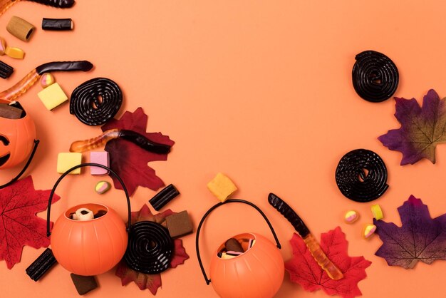 Świąteczne tło z fałszywymi jesiennymi liśćmi Halloweenowe cukierki i mały kosz z dyni JackOLantern