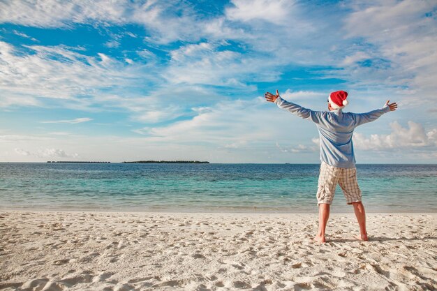 Świąteczne wakacje - mężczyzna w santa hat na tropikalnej plaży