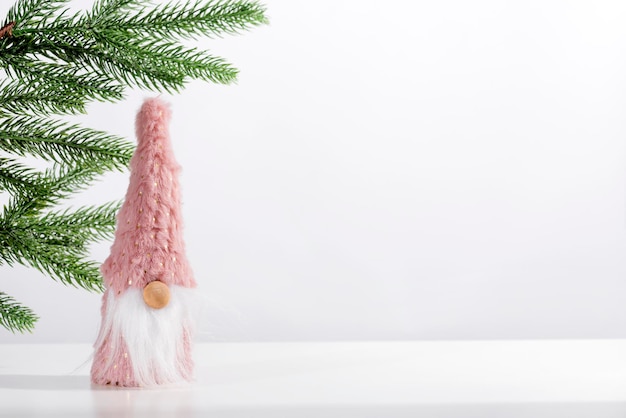 Świąteczny krasnal ze świątecznymi dekoracjami na tle gałęzi jodłowych