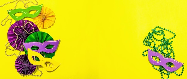 Zdjęcie Świąteczny mardi gras masquerade żółte tło tłusty wtorek maski karnawałowe koraliki tradycyjny wystrój symboliczne kolory modne twarde światło ciemny cień płasko ułożony format transparentu