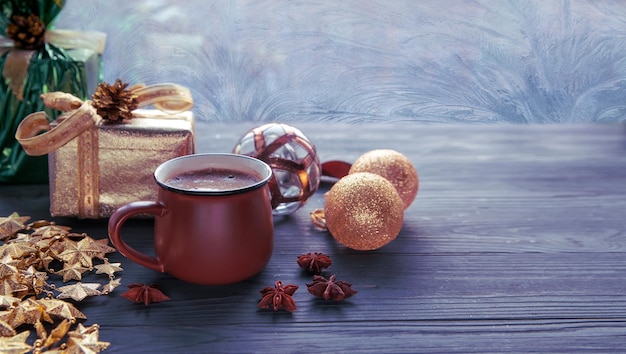 Świąteczny nastrój świąteczna atmosfera Filiżanka kawy złote ozdoby świąteczne i prezenty na tle okna w mroźne wzory