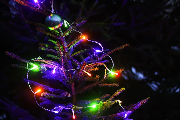 Świąteczny nowy rok tło z niewyraźne kolorowe światła na zdobione gałęzie jodły na zewnątrz.
