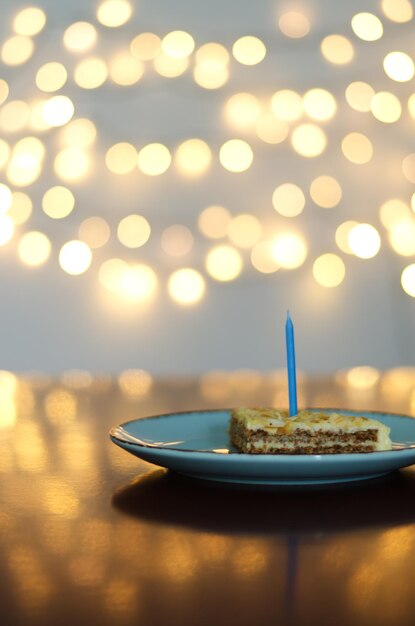Świąteczny tort urodzinowy z płonącymi świeczkami na jasnym tle bokeh. Kartka z życzeniami.
