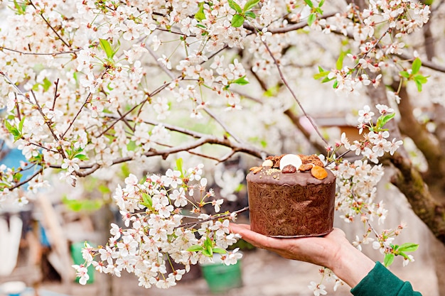 Świąteczny tort wielkanocny na tle kwitnących wiśni w ogrodzie.