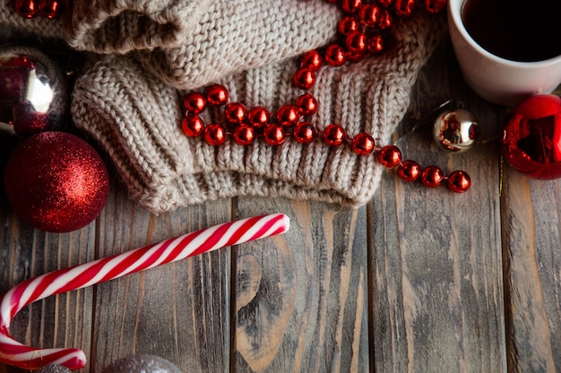 Świąteczny wystrój boże narodzenie tło. sezonowy projekt ze świątecznymi ozdobami i ozdobami. sweter z dzianiny błyszczące kulki koraliki i trzciny cukrowej na drewniane tła.