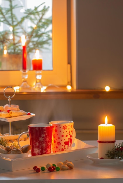 Świąteczny wystrój i czerwone filiżanki z gorącym napojem w kuchni