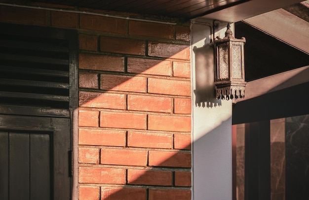 Światło i cień na powierzchni starej lampy ściennej retro na cegle i drewnianej ścianie domowej