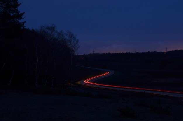 Zdjęcie Światłowe ścieżki na drodze pośród pola w zmierzchu