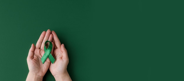 Zdjęcie Światowy dzień choroby afektywnej dwubiegunowej dorosłe ręce trzymające zieloną wstążkę dzień świadomości zdrowia psychicznego