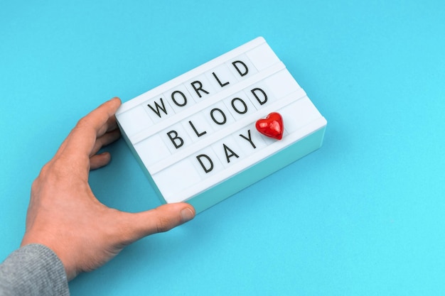 Światowy dzień dawcy krwi w tle mężczyzna trzyma lightbox z tekstem wiadomości i napisami