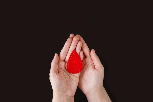 Światowy dzień hemofilii Koncepcja oddawania krwi transfuzja krwi Ręce kobiety trzymają kroplę krwi