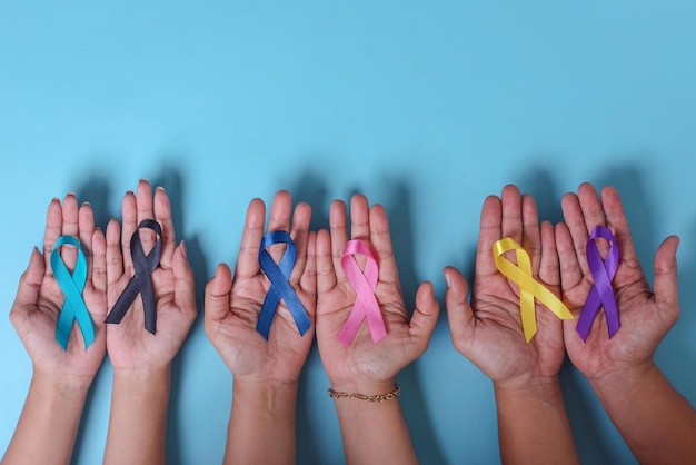 Światowy dzień walki z rakiem. Ręce ludzi trzymających kolorowe wstążki świadomości do wspierania ludzi