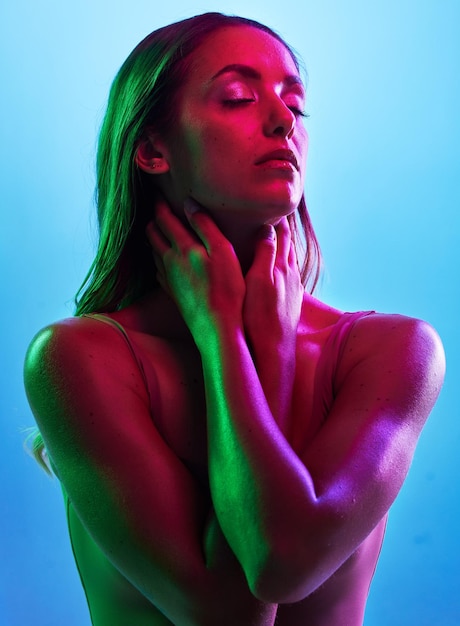 Świecące dłonie do pielęgnacji skóry lub dotyk w neonowym oświetleniu na izolowanym niebieskim tle z karkiem lub skórą Modelka lub kobieta mody w kreatywnym fantazyjnym zielonym różu lub światłach estetycznych w kosmetykach