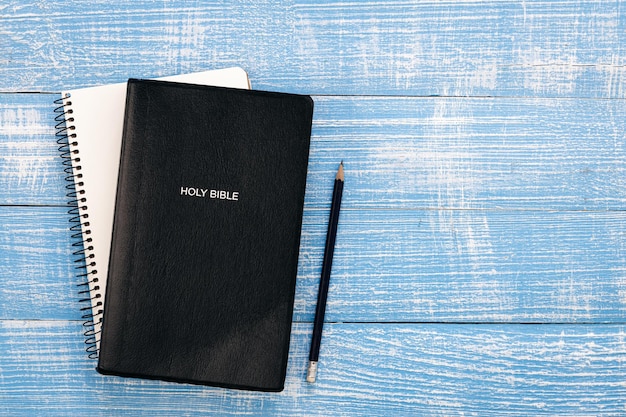 Święta biblia książka i notatnik na niebieskim drewnianym tle widok z góry miejsce na kopię