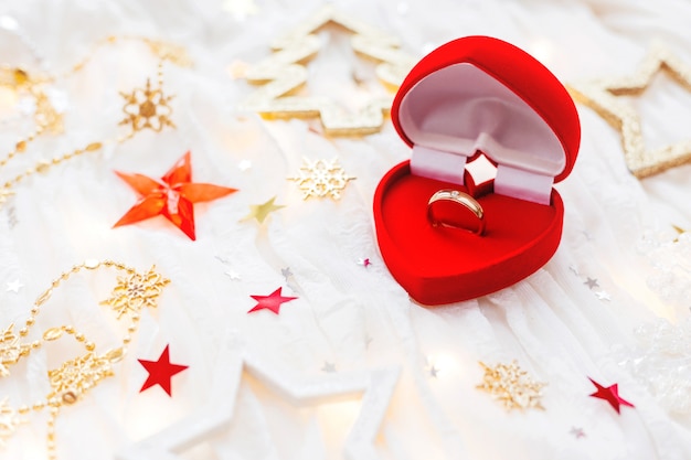 Zdjęcie Święta bożego narodzenia tło z dekoracjami i pierścionek zaręczynowy w pudełku serce prezent.