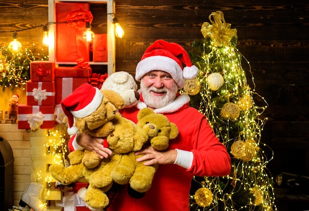 Zdjęcie Święta bożego narodzenia uśmiechnięte święty mikołaj z wieloma pluszowymi niedźwiedziami brodaty człowiek w kapeluszu świętego mikołaja z pluszowym