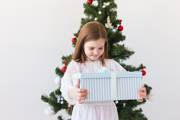 Święta, prezenty, boże narodzenie, koncepcja bożego narodzenia - szczęśliwa dziewczynka z pudełkiem.