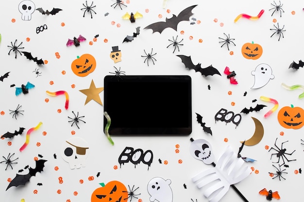 Zdjęcie Święta, technologia i koncepcja imprezy - dekoracje halloween i cukierki z tabletem na białym tle