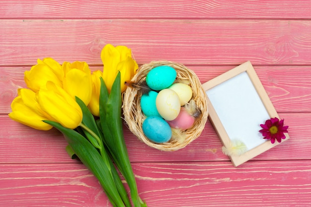 Święta Wielkanocne . Drewniana rama z Easter jajkami i tulipanami na kolorowym